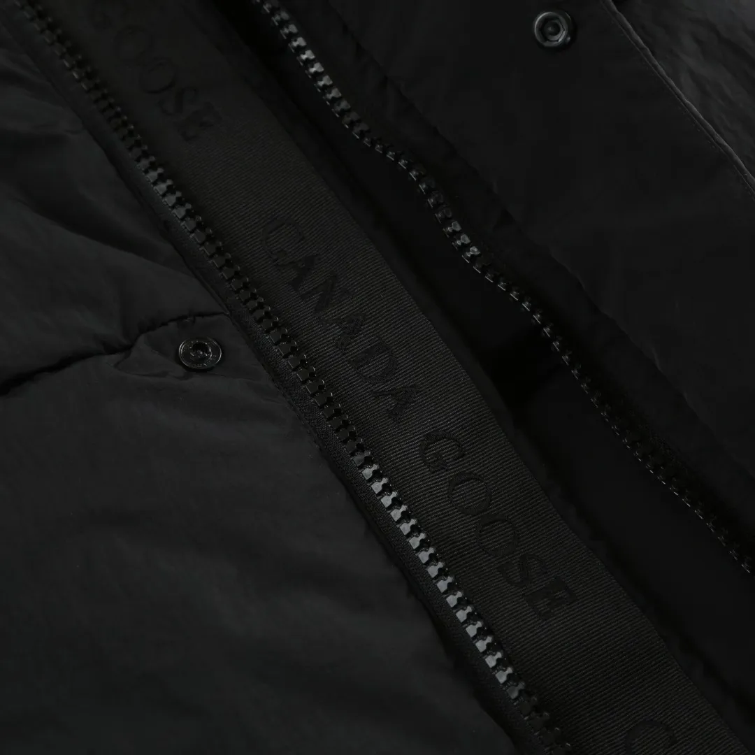 P740 Big Goose Logo Hooded Down Vest Fabric selection: The use of high-quality protective nylon fabric not only enhances the wear resistance of the surface, but also takes into account wind resistance, ensuring excellent performance in various harsh weather conditions.  90 national standard high-quality white duck down: selected high-loft down, weighing 170g, light and warm, with excellent temperature locking performance and good resilience.  Three-dimensional quilting process: Precision thread reinforcement to prevent velvet drilling and ensure that the fluffy and resilient elasticity lasts as new.  Details: Use polyester as the base for woven webbing, and use high-precision computer embroidery to decorate the brand letters on the webbing. The edges of the pattern are clear, the stitches are fine and even, and multiple layers of embroidery threads are stacked to enhance the three-dimensional effect. Accessories: One-to-one customized logo One-to-one customized zipper pendant One-to-one customized hem elastic buckle One-to-one customized snap button SIZE: S M L XL
